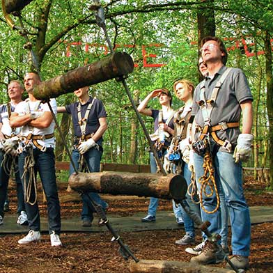 Eine Gruppe am Boden vor einem Kletterparcours tree2tree Hochseilgarten