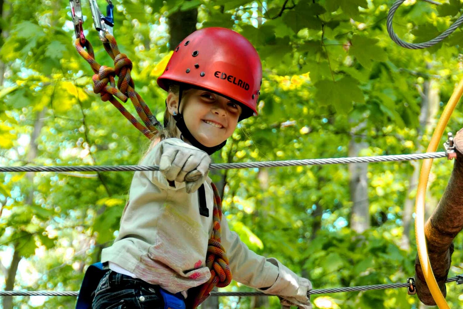 Ein Mädchen mit Helm beim Klettern im Hochseilgarten tree2tree