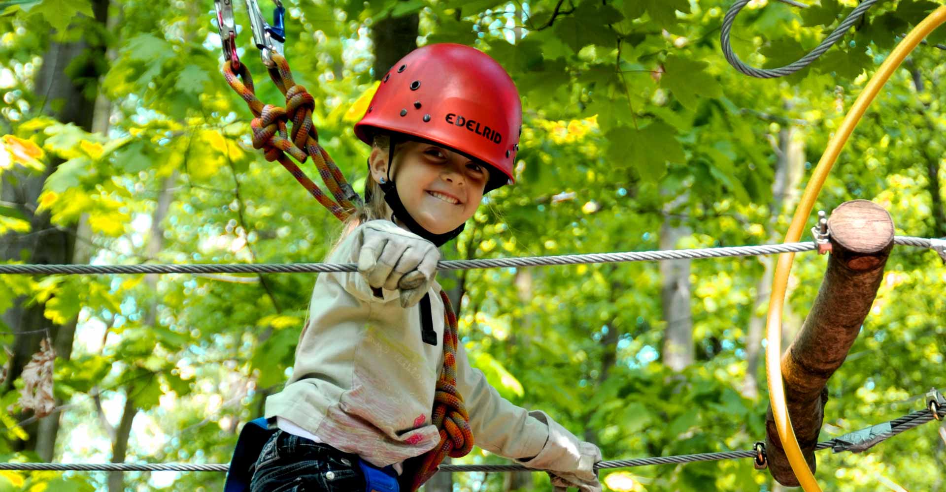 Ein Mädchen mit Helm beim Klettern im Hochseilgarten tree2tree