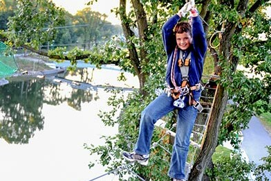 Ein Junge beim überqueren eines Parcourshindernisses im Hochseilgarten tree2tree