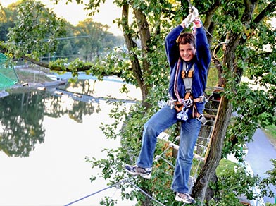 Ein Junge beim überqueren eines Parcourshindernisses im Hochseilgarten tree2tree