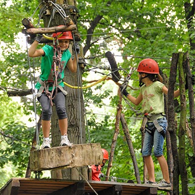 Zwei Mädchen im Hochseilgarten beim beschreiten der Hindernisse des Parcours tree2tree Hochseilgarten