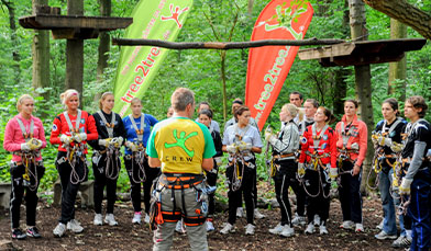 Eine Gruppe bekommt eine Einweisung von einem Crew-Mitglied tree2tree Hochseilgarten