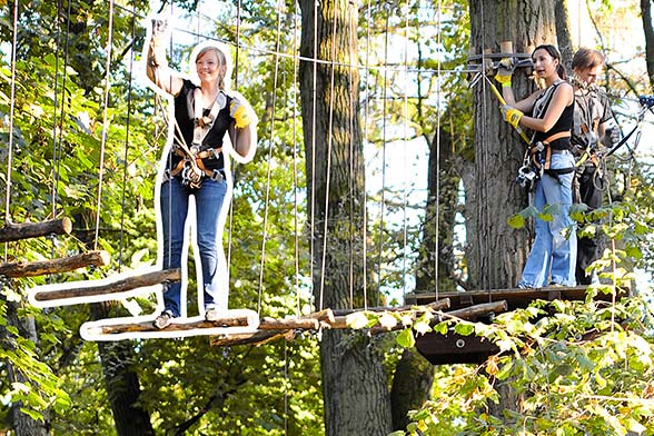 Drei Personen beim Überwinden eines Kletterparcoures im Hochseilgarten tree2tree